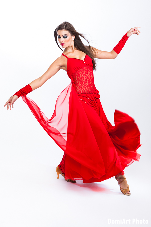 Táncos fotózás debrecen - másik irányba lépő modell, piros ruhában, ami libbel a mozgás és a szélgép hatására