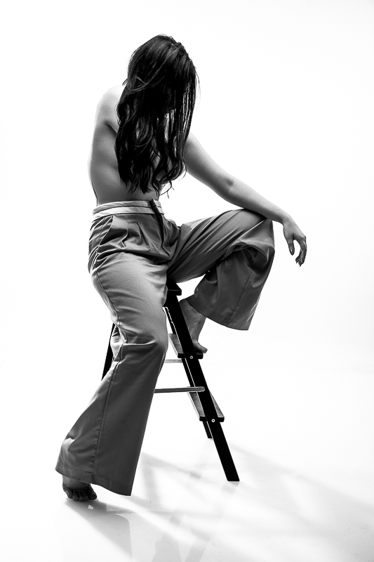 lifestyle glamour fotózás - újságot tart a kezében a lány, mikozben egy széken ül farmerben és fehérnemű felsőben