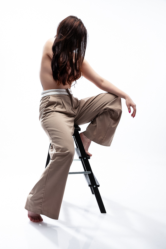 fashion glamour lépcsős széken ülő lány takarja kezével és hajával a melleit