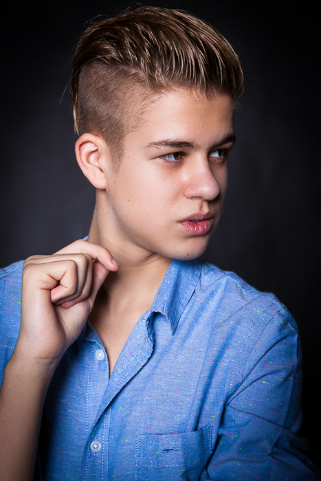 Közeli portré egy szőke srácról, oldalra néz, kék ingben van és mintha kiejtene valamit a száján