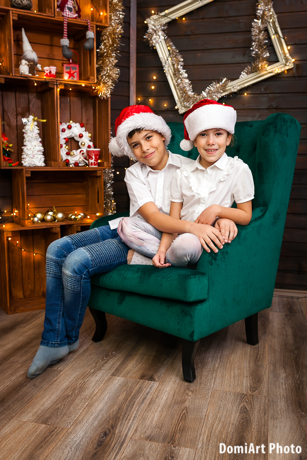 két testvér ül a hatalmas zöld fotelben, arany képkeret a falon - karácsonyi fotózás Debrecen