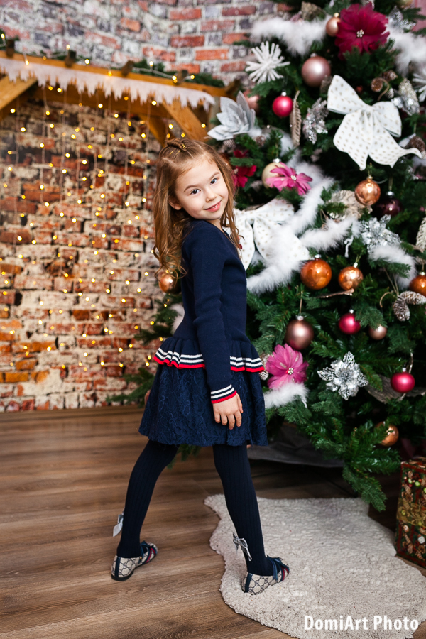 kislány egyéni karácsonyi fotózáson hatalmas karácsonyfa előtt