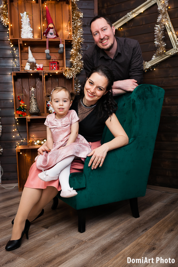 debreceni család karácsonyi fotózáson zöld fotelben, ledes épített háttérrel
