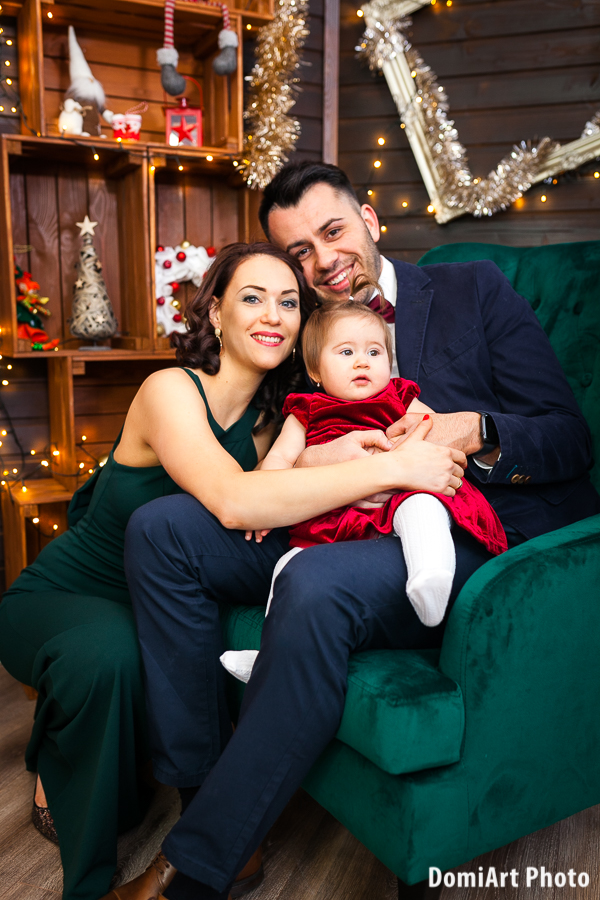 háromtagú család karácsonyi fotózáson ahol az apa ül a fotelben, az anyuka melletük guggol, a kisgyerek pedig apa ölében ül- Debrecen