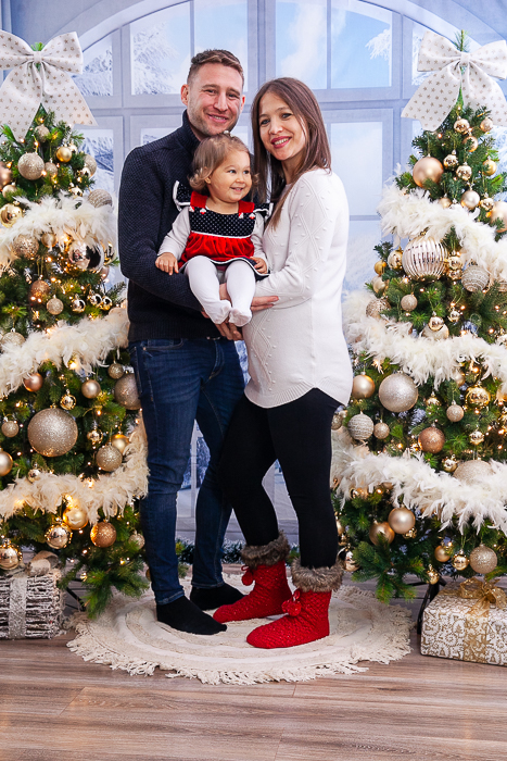 fehér barokk épített háttér előtti karácsonyi fotózás- kanapén ülő lányok, mögöttük apa - Debrecen