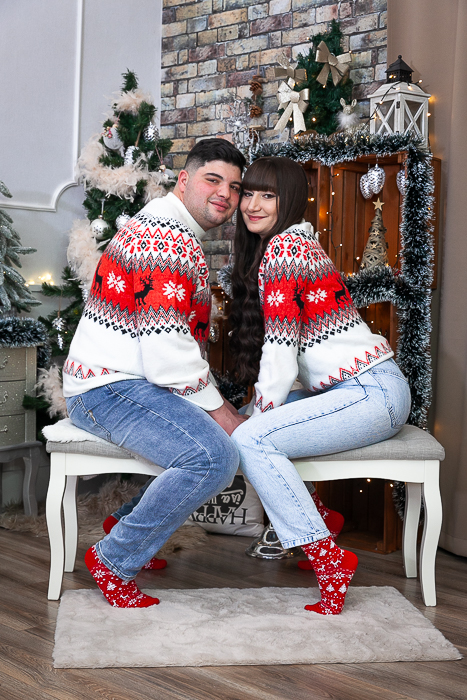 egymással szemben ülnek a párok a szófán, háttérben karácsonyi díszlet - karácsonyi páros fotózás debrecen