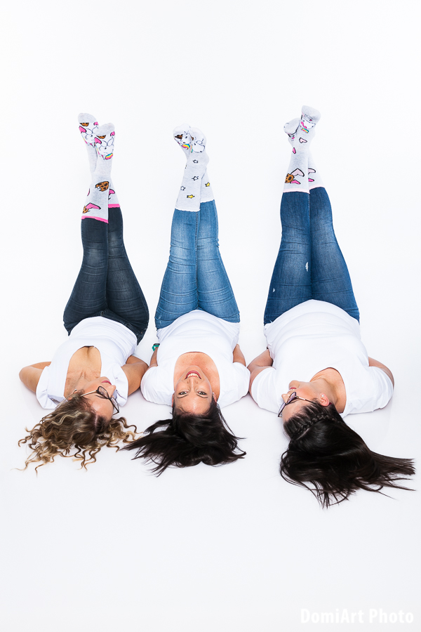lánybúcsú fotózás, vicces zokniban három lány fekszik a hátán és magasba tartja a lábát