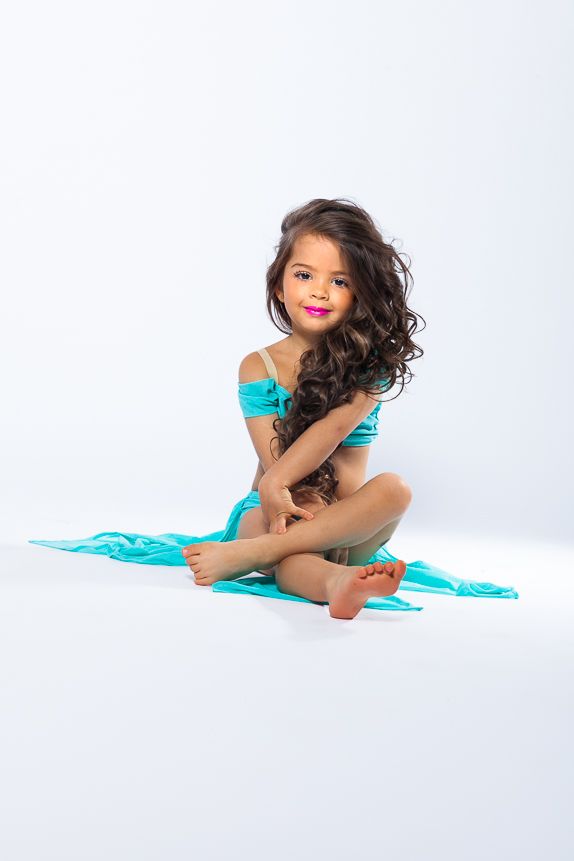 kis 4 éves kislány csodaszép táncos ruhában ül és a lábaival ülő pózt alkot - hosszú göndör haja a derekáig ér - táncos fotózás debrecen
